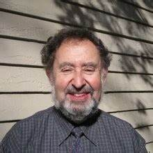 Man with gray hair and beard wearing a dark button-up shirt