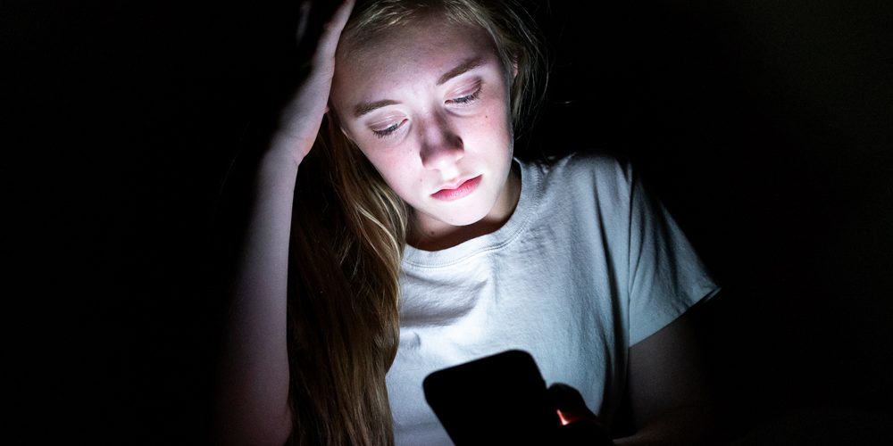 Lonely teenager looking at her phone.