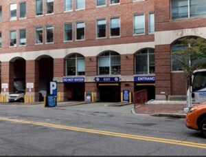 Parking garage entrance beneath a brick building, with lanes marked “Do Not Enter,” “Exit,” and “Entrance.”