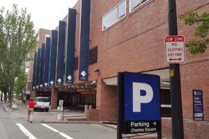 Charles Square building entrance with signs for public parking and a tow zone