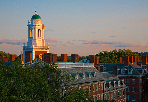 Historic brick campus buildings with a white cupola glowing at sunset